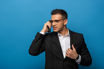 Handsome businessman talking on telephone on blue background