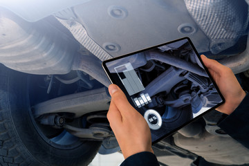 Serviceman repairing a car using augmented reality application.