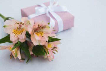 Flowers and gift box on light grey background. Holiday, gifts and discount concept. Close up, copy space