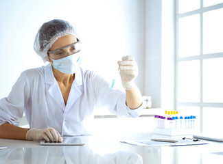 Professional female scientist in protective eyeglasses researching tube with reagents in laboratory. Concepts of medicine and research