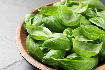 Fresh basil leaves in wooden bowl, closeup