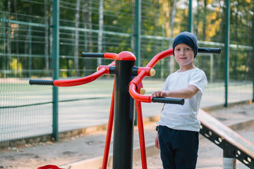 Fototapeta premium Little boy on street public sports training equipment
