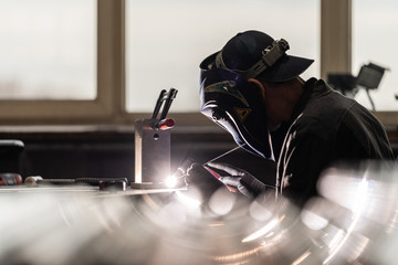 Schweisser mit Maske beim Arbeiten in einer Fabrik, Halle