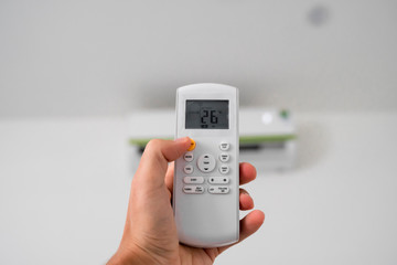 Man's hand using remote controler. Hand holding rc and adjusting temperature of air conditioner...