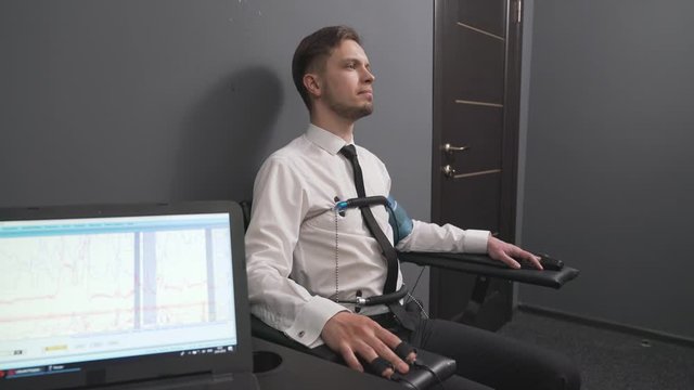 Serious man with pulse electrodes connected to polygraph