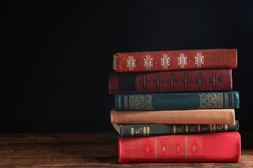 Collection of different books on wooden table against dark background. Space for text