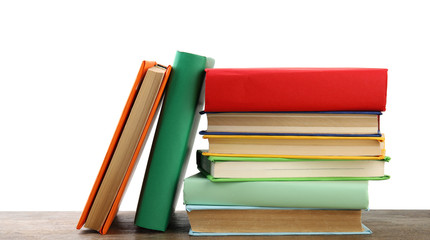 Stack of colorful books on wooden table against white background
