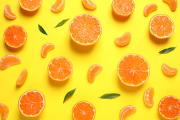 Flat lay composition with halves of fresh ripe tangerines and leaves on yellow background. Citrus fruit