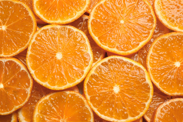 Slices of fresh ripe tangerines as background, top view. Citrus fruit