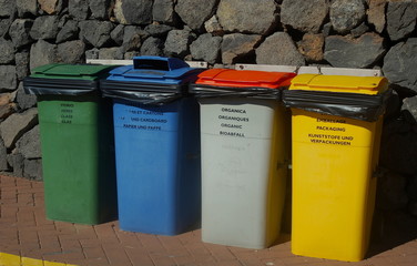 Recycling containers displaying different languages and color uses
