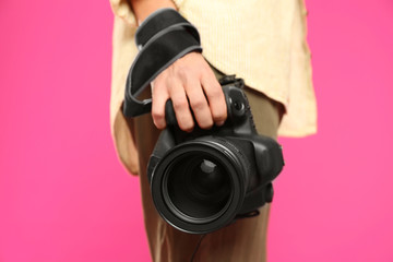 Professional photographer with modern camera on pink background in studio, closeup