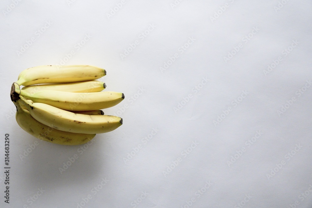 Poster high angle shot of fresh delicious bananas on a white surface with an empty space for text