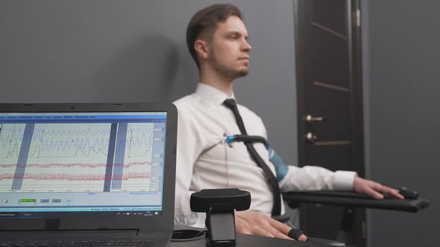 Bearded man during polygraph test in grey office