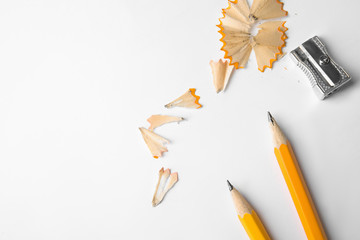 Graphite pencils, shavings and sharpener on white background, top view