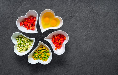 Top view of ingredients for scrambled eggs on black stone background