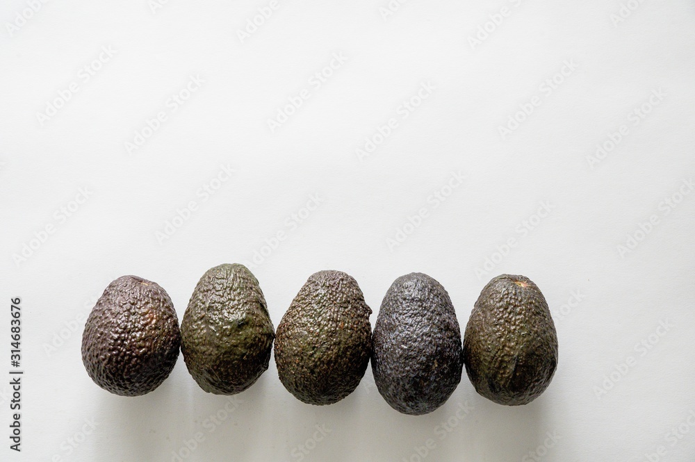 Poster lineup of fresh delicious avocados on a white surface with an empty space for text