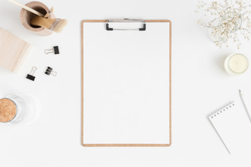 Top view of a wooden clipboard mockup with a gypsophila in vase and workspace accessories on a...