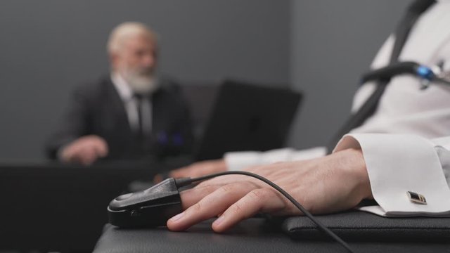 Aged man in black suit testing with detector lie young guy