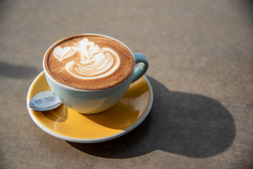 Latte cup with latte art on yellow plate