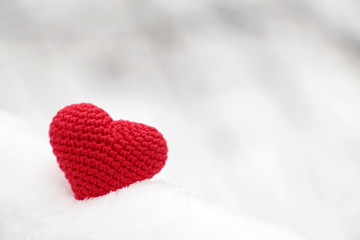 Obraz premium Valentine heart in winter forest. Red knitted heart, symbol of romantic love in the snow, concept of Valentines day