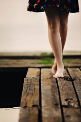 A girl walks on a wooden bridge to the lake. The bridge on the lake. Beautiful barefoot.