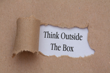 Think Outside The Box appearing behind torn brown paper.