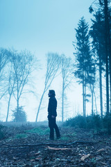 Man in black jacket and trousers in foggy winter forest.