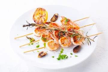 grilled shrimp on skewers. Grilled seafood on skewers with spices, herbs and lemon. delicious prawn. White plate. White background