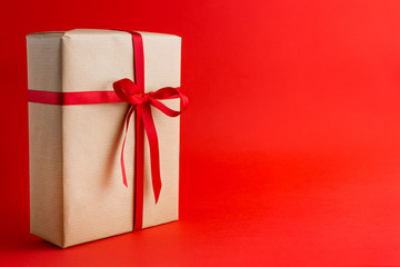 Brown gift box with red ribbons on Red background. Place for text. Gift for Christmas, Valentine holiday or a birthday.