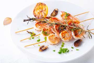 grilled shrimp on skewers. Grilled seafood on skewers with spices, herbs and lemon. delicious prawn. White plate. White background