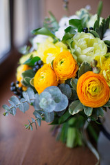  A large beautiful bouquet of cotton, eucalyptus, tulips, roses of beautiful yellow, orange and white colors on a wooden background. Holiday gift concept, mother's day, birthday, wedding