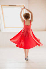 A girl in a bright pink dress is dancing in a room bathed in sunlight