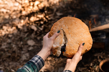 Closeup of fresh rustsic bread in a woman's hand. The background of the forest