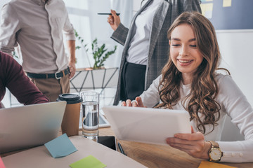 cropped view of businessmen near cheerful businesswoman using digital tablet