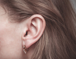 Female ear with a golden earring