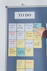 cropped view of scrum master pointing with finger at sticky note with off like mode letters