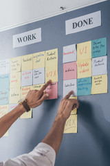 cropped view of businessman pointing with fingers at sticky notes with letters in office