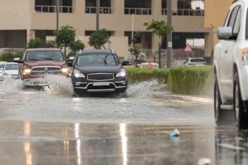 Cars driving trough big water pond after heavy rains fall in Dubai