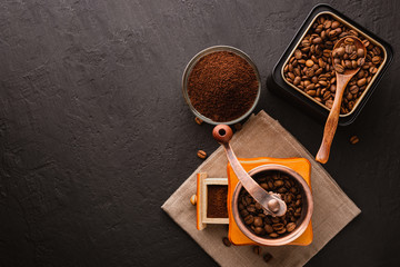 Coffee beans in a black metal jar, cotton cloth, vintage coffee grinder, wooden brown spoon on a dark concrete background