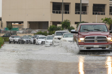 Obraz na płótnie Canvas Cars driving trough big water pond after heavy rains fall in Dubai