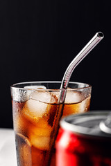 Glass glass with soda and ice ,metal reusable straw for cocktails,can on foreground