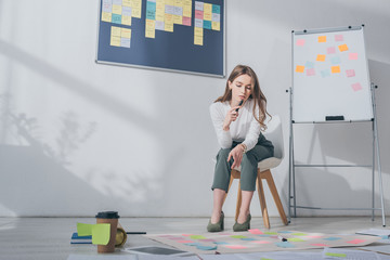 beautiful businesswoman sitting on chair near sticky notes on floor