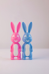 Cute bunnies, happy lovers couple together on light background, creative Valentine's day card. Family love, relationship,dating concept. Easter banner, wallpaper. Pink and blue rabbits. Minimal style.