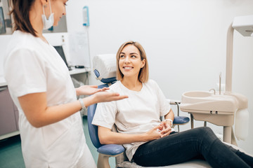 young caucasian woman sit litlen to doctor's recommendations before teeth treatment, smiling caucasian female in dentist room