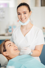 portrait of female dentist in white doctor's uniform standing in office near equipment and look at...