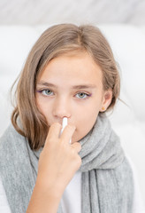 Close up Sick girl with flu using nose spray at home