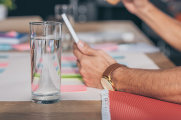 selective focus of glass of water near businessman using digital tablet