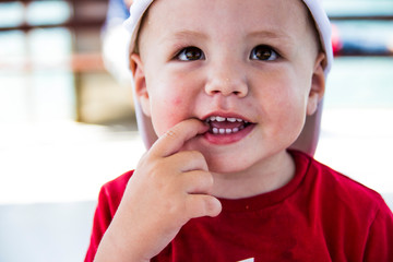 4 Jahre alter Junge schaut verschmitzt mit Finger im Mund