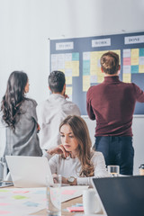 selective focus of attractive businesswoman using laptop near scrum masters