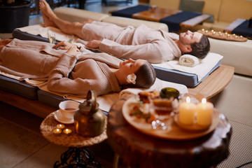 young caucasian man and woman wearing bathrobe, lying down and relxing at spa in beauty salon. Relax and healthy lifestyle concept